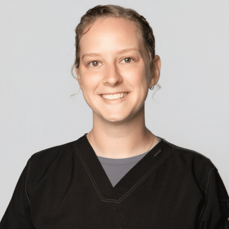 A person with short hair smiles and wears a black top.
